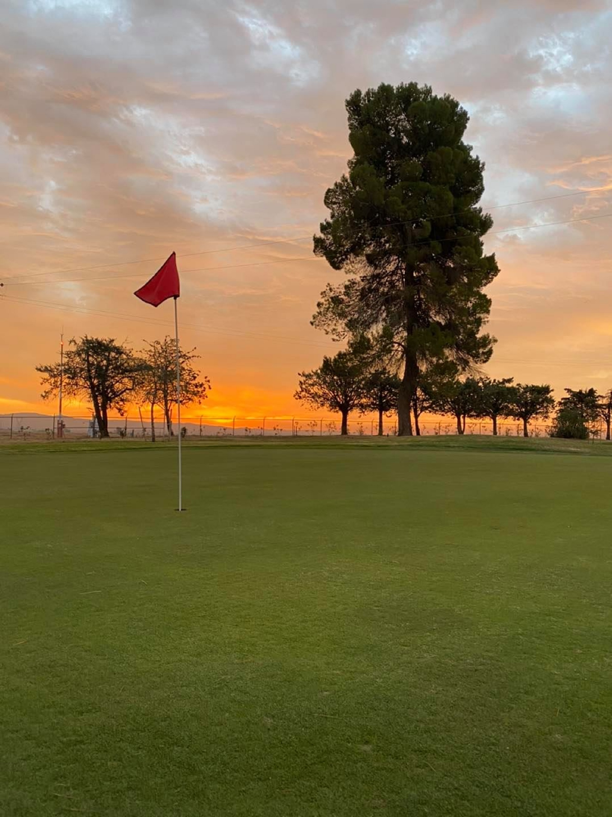 Flag on golf course at sunset